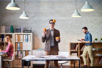 
		Eine Mann jongliert mit Obst im Büro
	